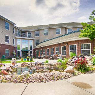 A landscaped garden with a pond in front of a residential building.