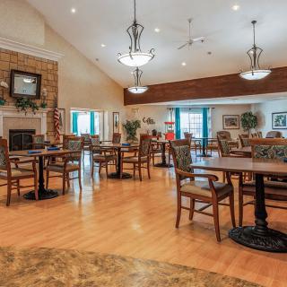 A cozy dining area with wooden tables and chairs, featuring warm lighting and a homey atmosphere.