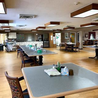 A spacious dining area with tables and chairs arranged neatly on a wooden floor.