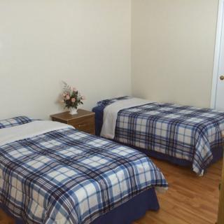 A simple bedroom with two twin beds featuring plaid bedding and a nightstand in between.