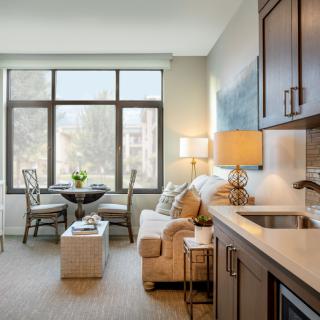 A cozy modern apartment featuring a bright living room with a kitchenette and ample natural light.