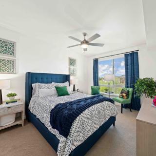 A modern bedroom with a large bed, blue and white color scheme, and a view through large windows.