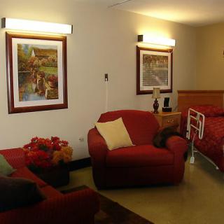 A cozy living room with red sofas, paintings on the wall, and warm lighting.
