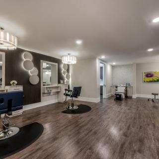 A modern salon interior with elegant decor, featuring chairs, mirrors, and warm lighting on a wooden floor.