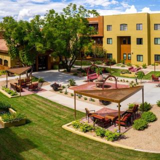 A beautifully landscaped courtyard with seating areas and lush greenery in front of a multi-story building.