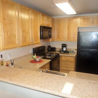 A modern kitchen featuring wooden cabinets and a granite countertop with stainless steel appliances.