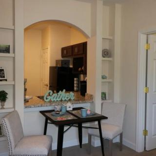A cozy dining nook with two chairs and a table situated near an open kitchen.