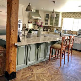 A modern kitchen with a central island, featuring bar stools and pendant lighting.
