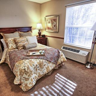 A cozy bedroom with a neatly made bed, warm lighting, and tasteful decor.