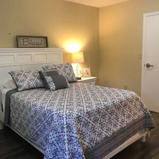 A cozy bedroom featuring a neatly made bed with patterned bedding, a bedside lamp, and warm lighting.
