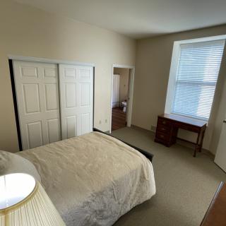 A simple bedroom with a bed, closet, and a desk near the window.