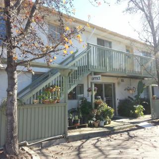 A two-story residential building with external stairs and surrounding trees.