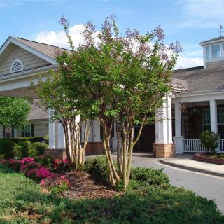 A charming building surrounded by a landscaped garden with trees and blooming flowers.