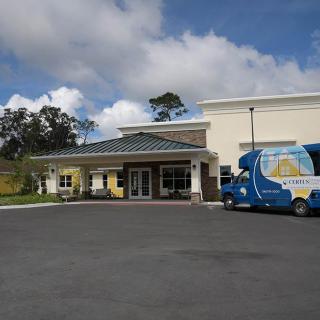 A commercial building with a van parked in the lot under a cloudy sky.