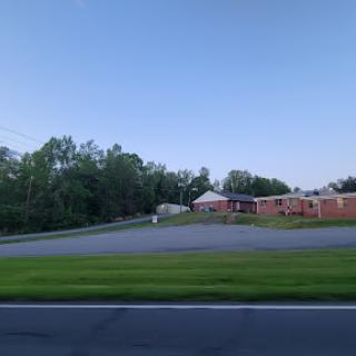 A peaceful scene of a building surrounded by trees and open space, captured during twilight.