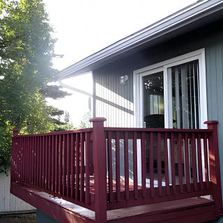 A view of a wooden deck attached to a house with sliding glass doors.
