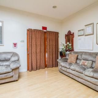 A cozy living room with a sofa and armchair, featuring hardwood floors and decorative elements.