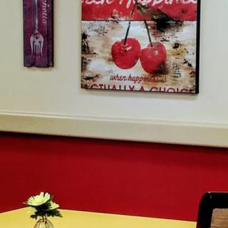 A cozy dining area with a cherry-themed poster on a red wall.