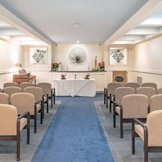 A chapel interior with rows of chairs facing an altar, prepared for a ceremony.