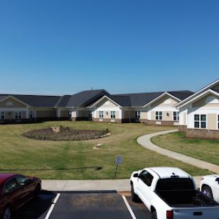 A view of residential buildings surrounded by landscaped grass and a clear blue sky.