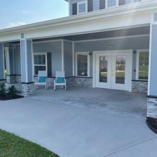 A spacious porch with chairs and a view of the house exterior.