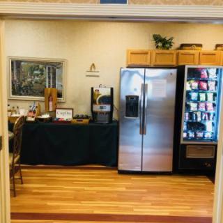 A cozy break room featuring a vending machine, a coffee station, and a refrigerator.