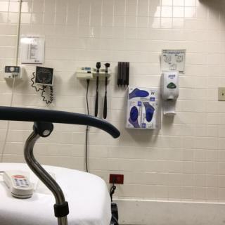 A hospital examination room featuring medical equipment and a bed.