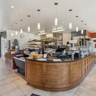 Inside view of a modern caf featuring a wooden counter and an organized kitchen area.