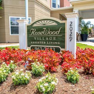 Entrance sign for Rosewood Village Assisted Living surrounded by vibrant flowers.