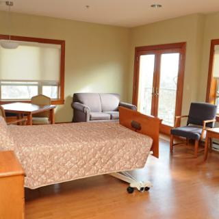 A spacious, well-lit hospital room featuring a bed and seating area.