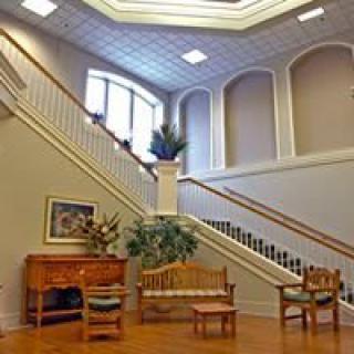 A well-lit lobby with a grand staircase and elegant furniture.