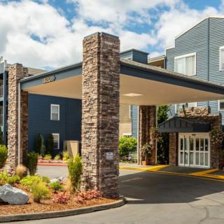 Modern hotel entrance with stone pillars and landscaped surroundings.