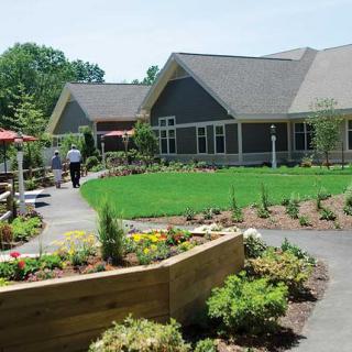 A beautifully landscaped garden with a pathway leading to modern buildings.