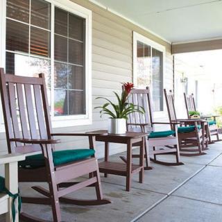 A serene porch featuring wooden rocking chairs and a small table with a potted plant, perfect for relaxation.