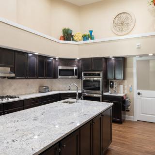 A modern kitchen with dark cabinets and a marble countertop.