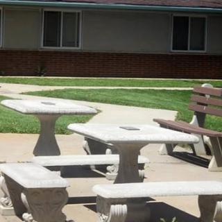 Concrete tables and benches set in an outdoor courtyard with grass.