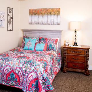 A cozy bedroom with colorful bedding and decorative touches.