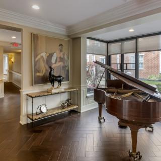 A stylish living room featuring a grand piano and elegant decor with large windows.