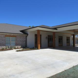 A modern residential building with a spacious driveway under a clear blue sky.