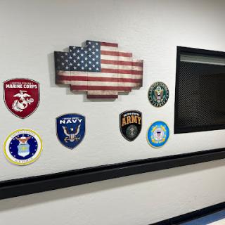 A display of military emblems and an American flag on a wall.