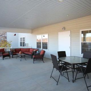 A spacious outdoor patio featuring comfortable seating with a sofa and chairs, under a covered area.