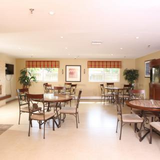 A well-lit dining area with multiple tables and chairs, featuring modern decor and large windows.