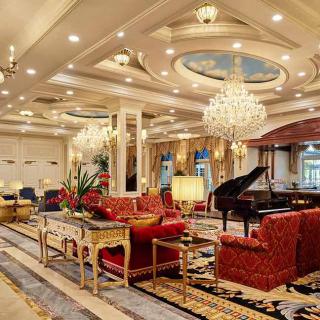 A luxurious living room interior adorned with chandeliers, elegant furniture, and a grand piano.