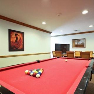 A cozy billiard room featuring a red-felt pool table and comfortable seating area.