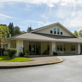 A single-story residential building with a driveway and well-maintained lawn in a suburban setting.