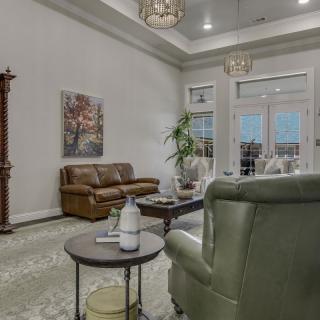 A cozy living room with a sofa, armchair, and coffee table, featuring elegant decor and soft lighting.