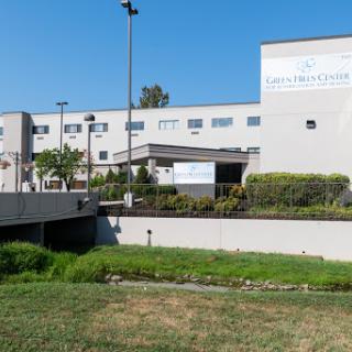 A modern healthcare facility surrounded by greenery under a clear blue sky.