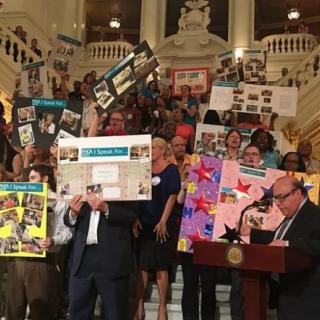 A group of people holding colorful posters at an indoor event on a staircase.