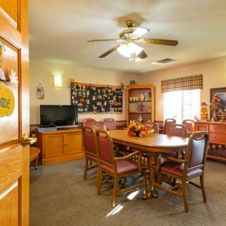 A cozy dining room featuring a wooden table with chairs, a television, and decorative elements on the walls.