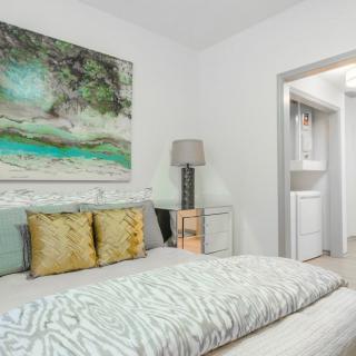 A modern bedroom with stylish decor, featuring a bed with patterned bedding, decorative pillows, and a large artwork piece above the headboard.